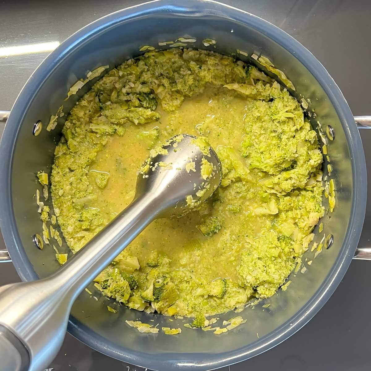 Healthy broccoli soup ingredients being puréed with an immersion blender