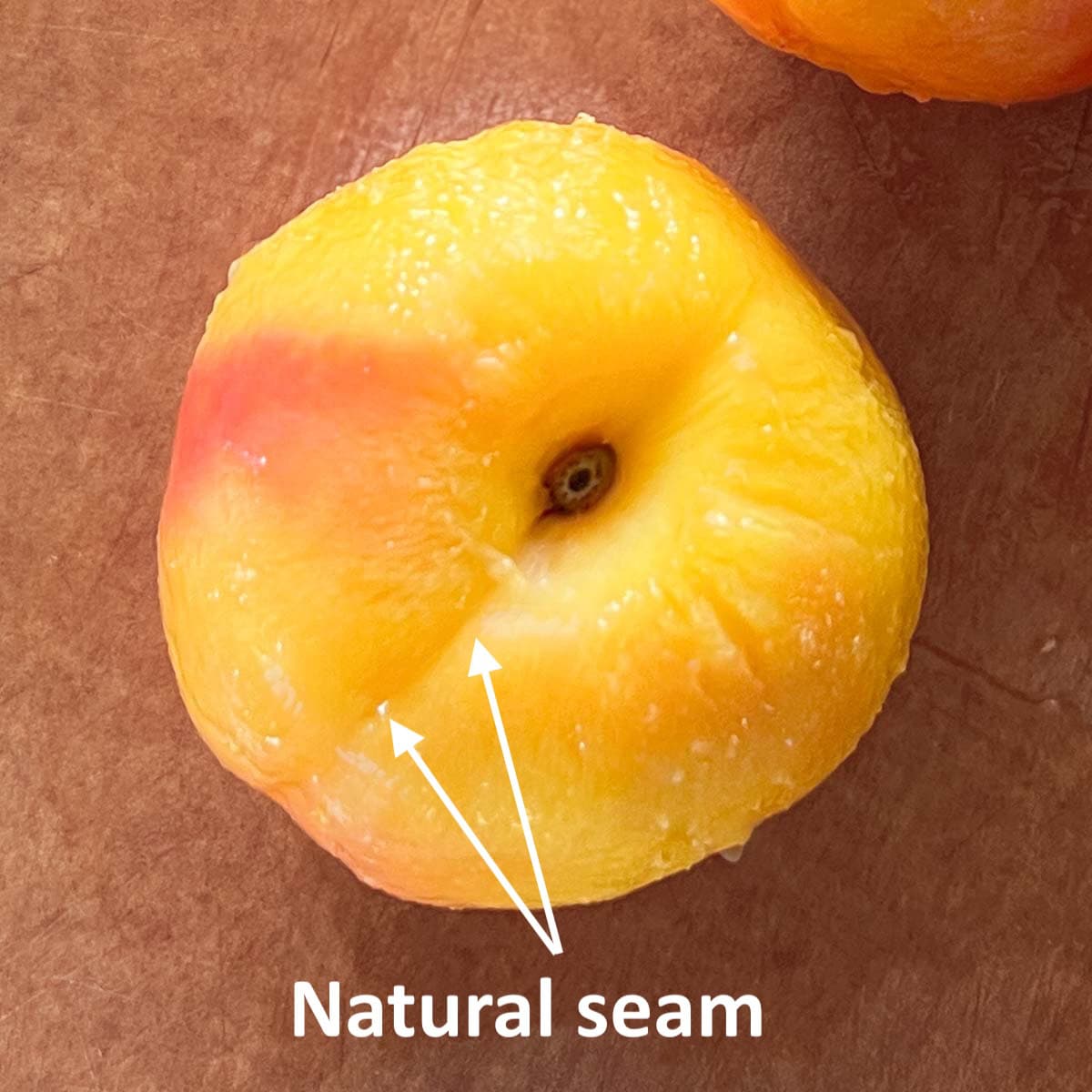 Peeled peach with a clearly identified seam down the middle for cutting into.