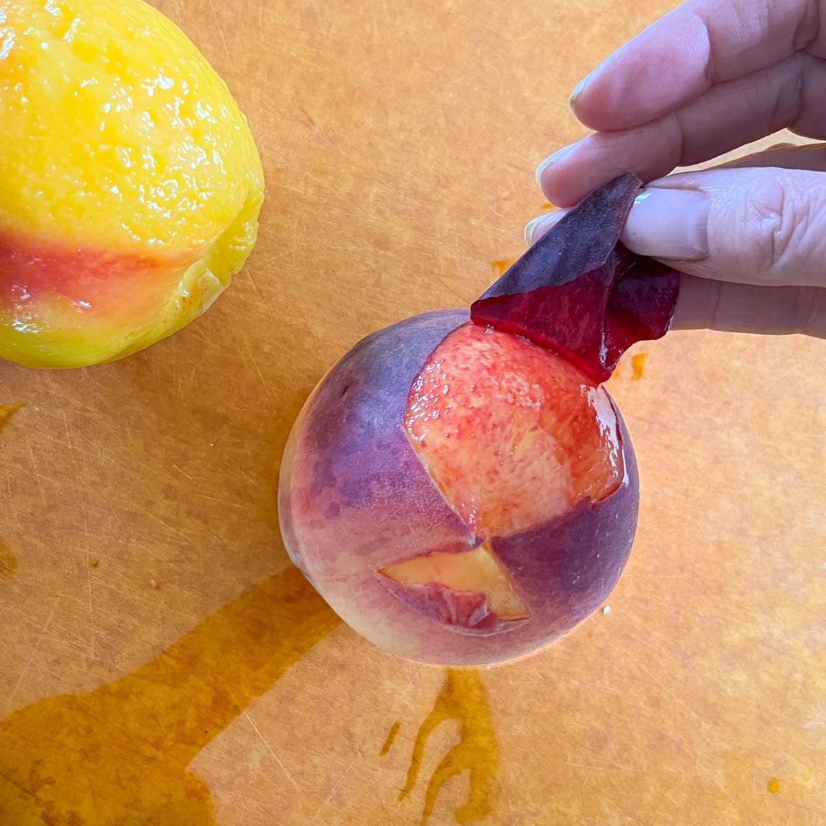 Skin being carefully peeled off a blanched peach.