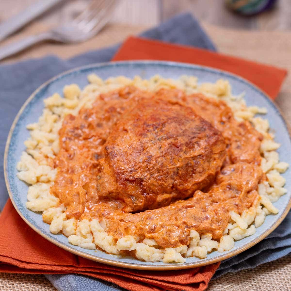 blue plate holding an individual portion of Hungarian Chicken Paprikash with Dumplings