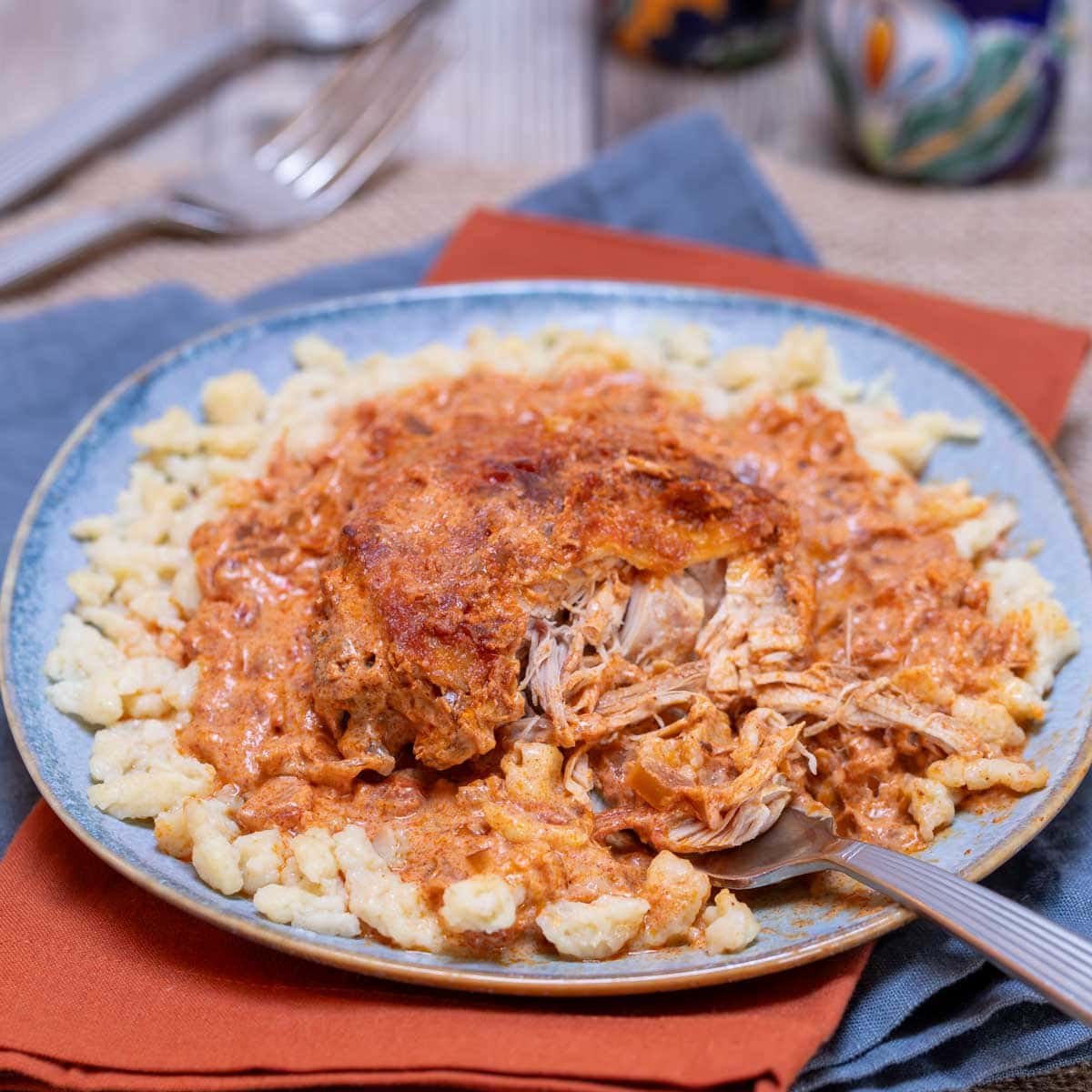 blue plate holding an individual portion of Hungarian Chicken Paprikash, showing the tenderness of the cooked chicken