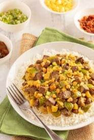 white plate holding Lamb Curry, with 4 small bowls alongside, showing condiments