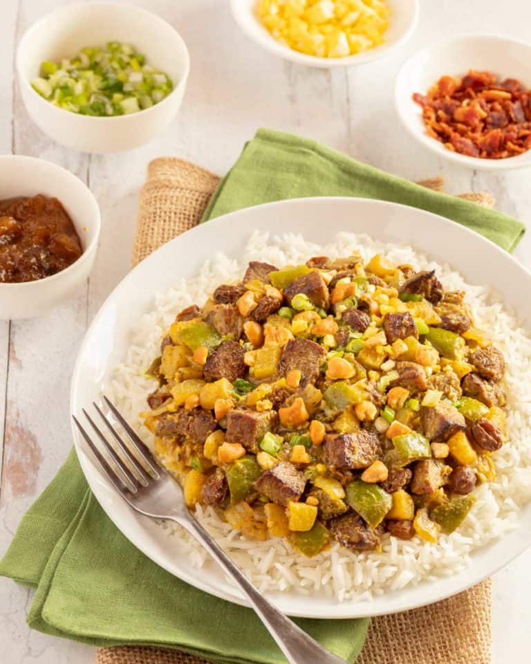 white plate holding Lamb Curry, with 4 small bowls alongside, showing condiments