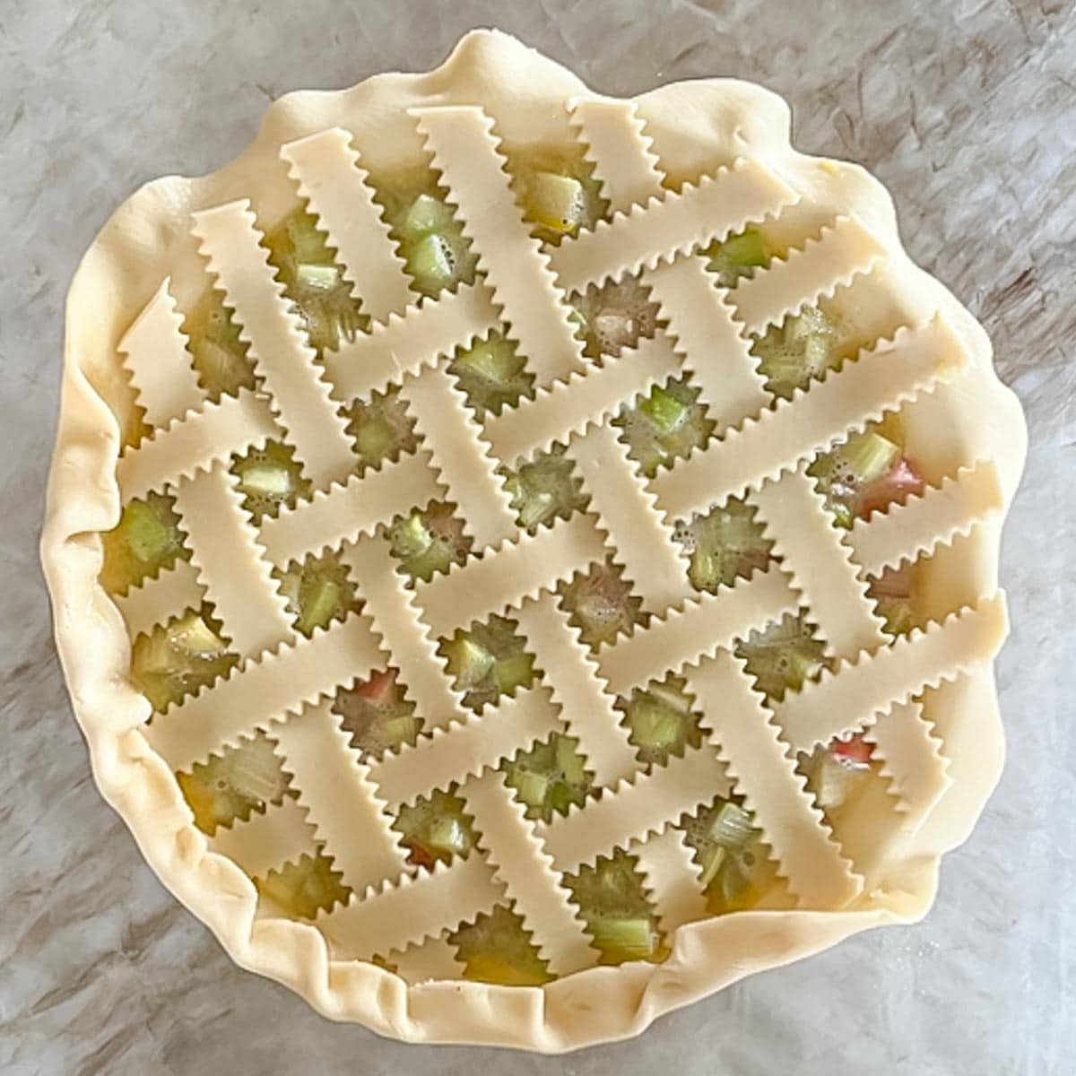 filled pie with completed woven lattice top, showing how to fold outside edge over top of lattice ends