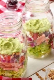 Large mason jars filled with Layered Salmon Salad With Avocado Dressing