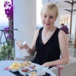 Lee sitting at a table holding a martini, with tapas on the table