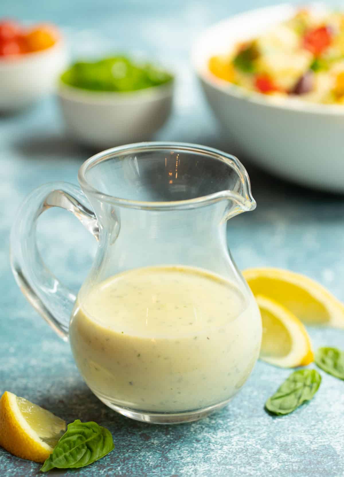 Small glass pitcher filled with Lemon-Basil Tahini Dressing