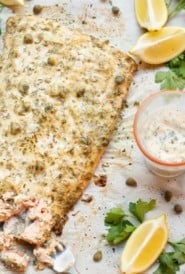 Salmon filet with lemon caper sauce on top and on the side