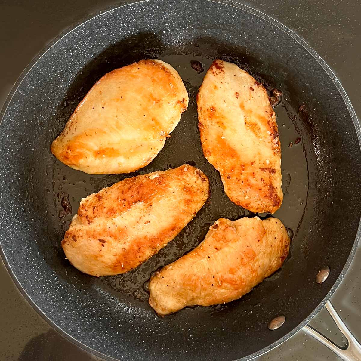 4 breasts in a skillet, showing how they should look when golden brown