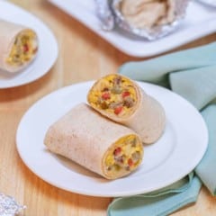 white plate holding one Breakfast Burrito, cut in half to show insides