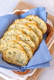 small basket lined with a blue napkin and filled with slices of Parsley Parmesan Crostini Bread