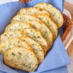 small basket lined with a blue napkin and filled with slices of Parsley Parmesan Crostini Bread