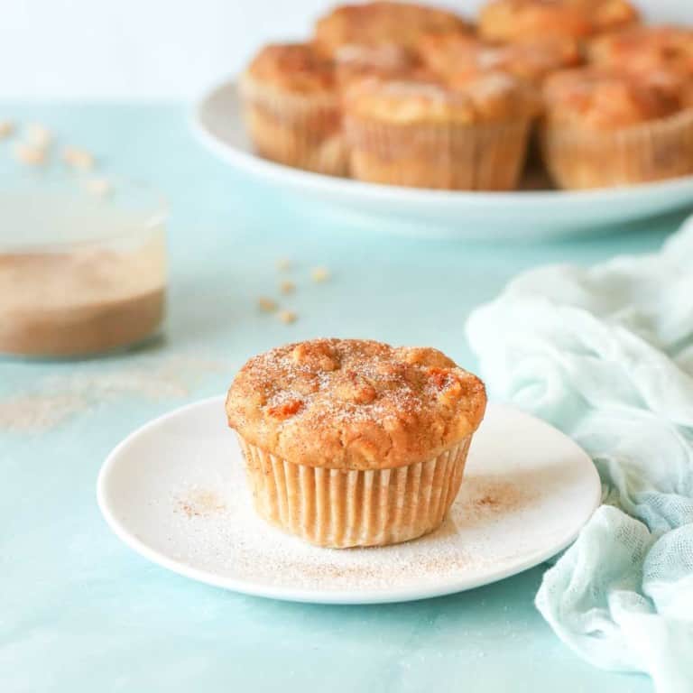 single Peach Muffin on a plate wtih a platter holding more muffins in back