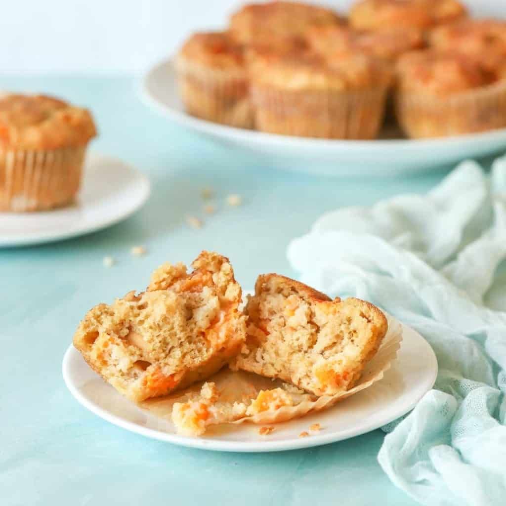 single Peach Muffin split open in front with platter holding more muffins in the background