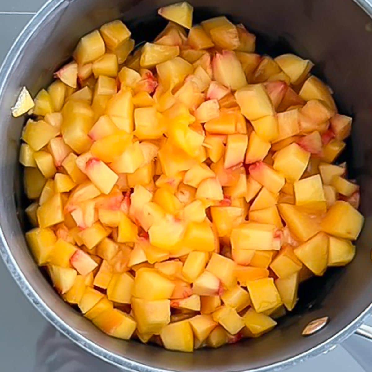 Chopped peaches in a saucepan, showing how large to chop the peaches