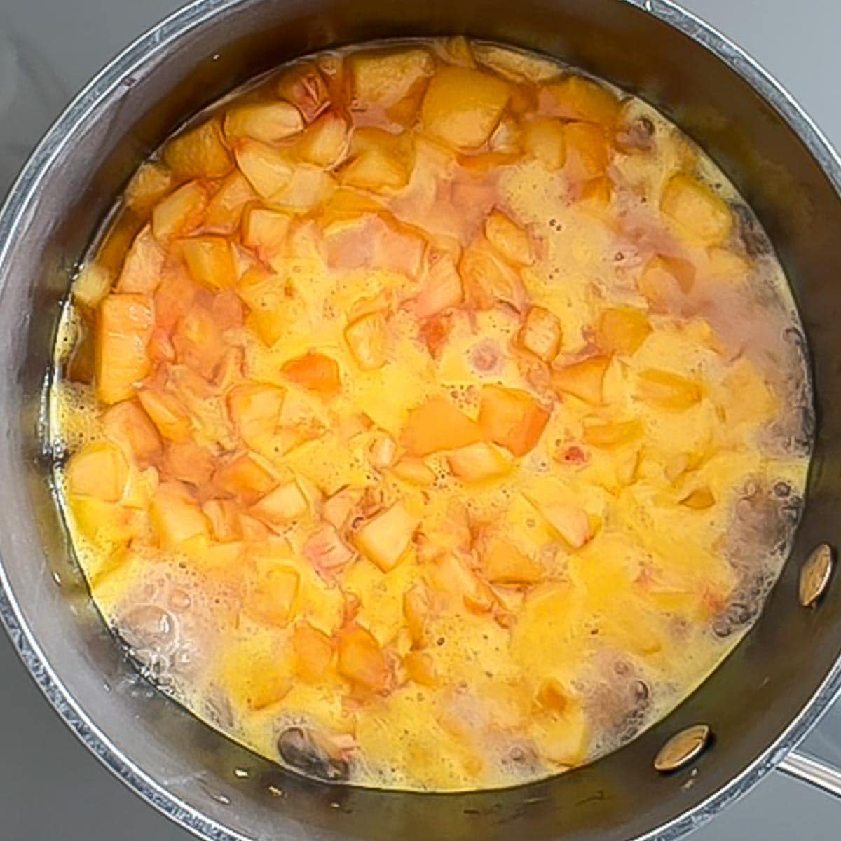 Peach sauce cooking, showing what simmer should look like