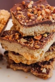 four pecan chocolate toffee bars stacked with one leaning on the side