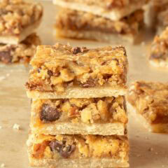 Pecan Pie Bars cut into individual bars and 3 stacked on a wooden board, showing the inside of the cookie