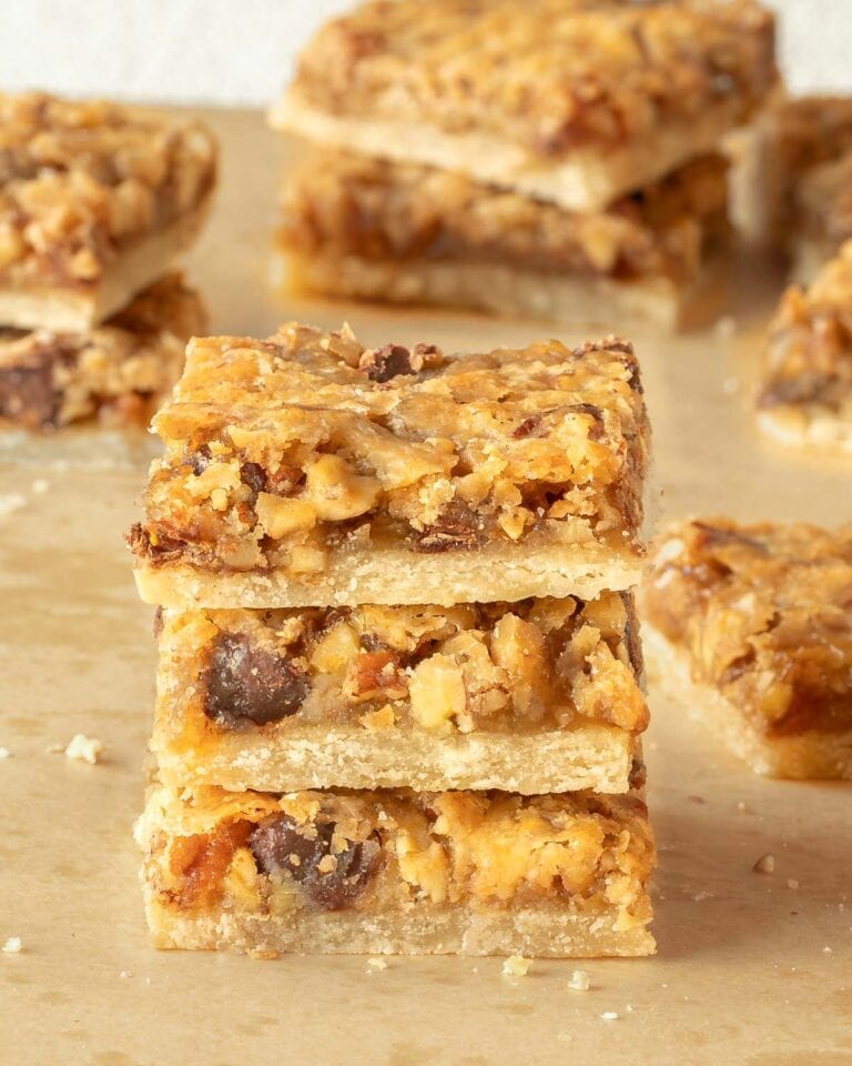 Pecan Pie Bars cut into individual bars and 3 stacked on a wooden board, showing the inside of the cookie