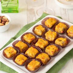 Rectangular white platter holding 15 Pimento Cheese Appetizers with Green Chiles. a cocktail and nuts are partially visible in the background.