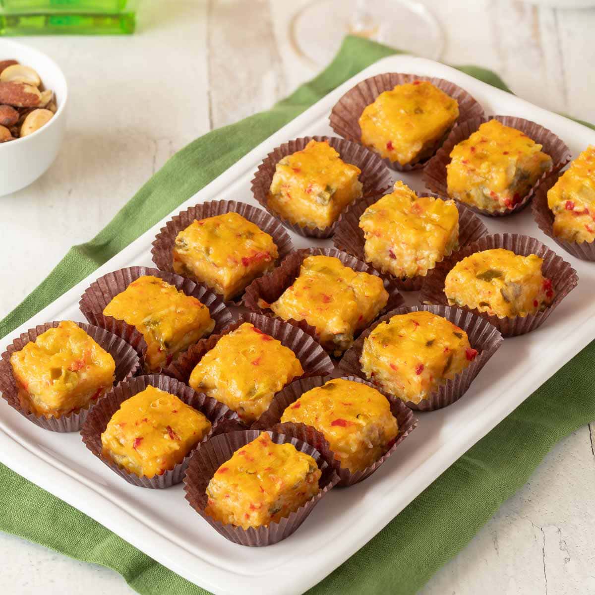 Closer view of 15 Pimento Cheese Appetizers with Green Chiles in paper candy cups sitting on a white platter.