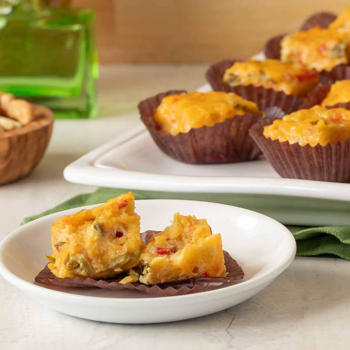 Small plate showing a Pimento Cheese Appetizer with Green Chiles broken in half, with a platter holding more in the background.