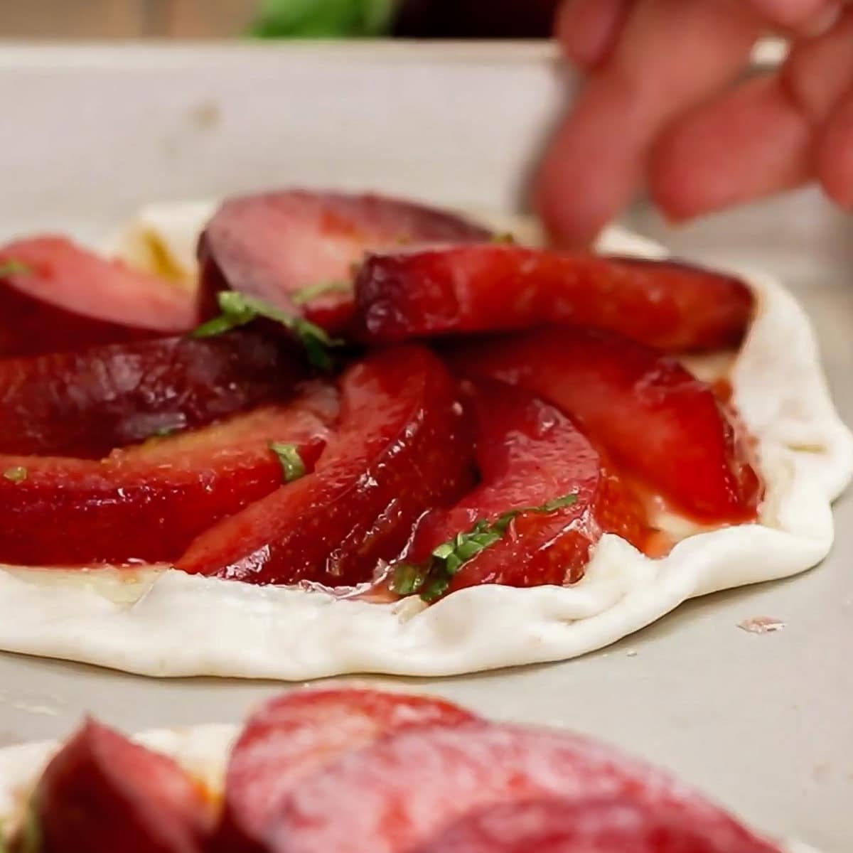 Process shot showing how to fold pastry edge over plum slices