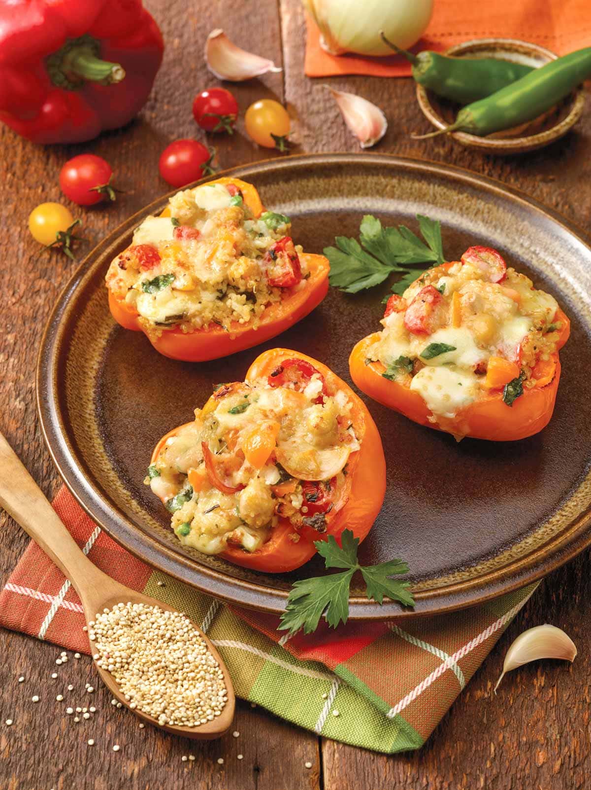 Three Stuffed Bell Peppers with Quinoa on a brown plate, with ingredients surrounding the plate