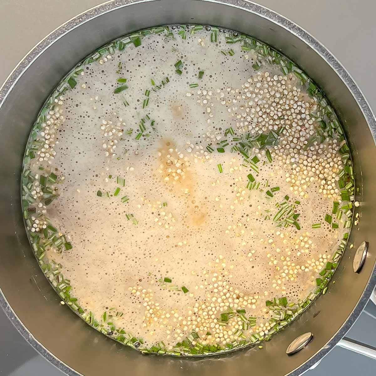 quinoa cooking in vegetable stock with rosemary and garlic powder