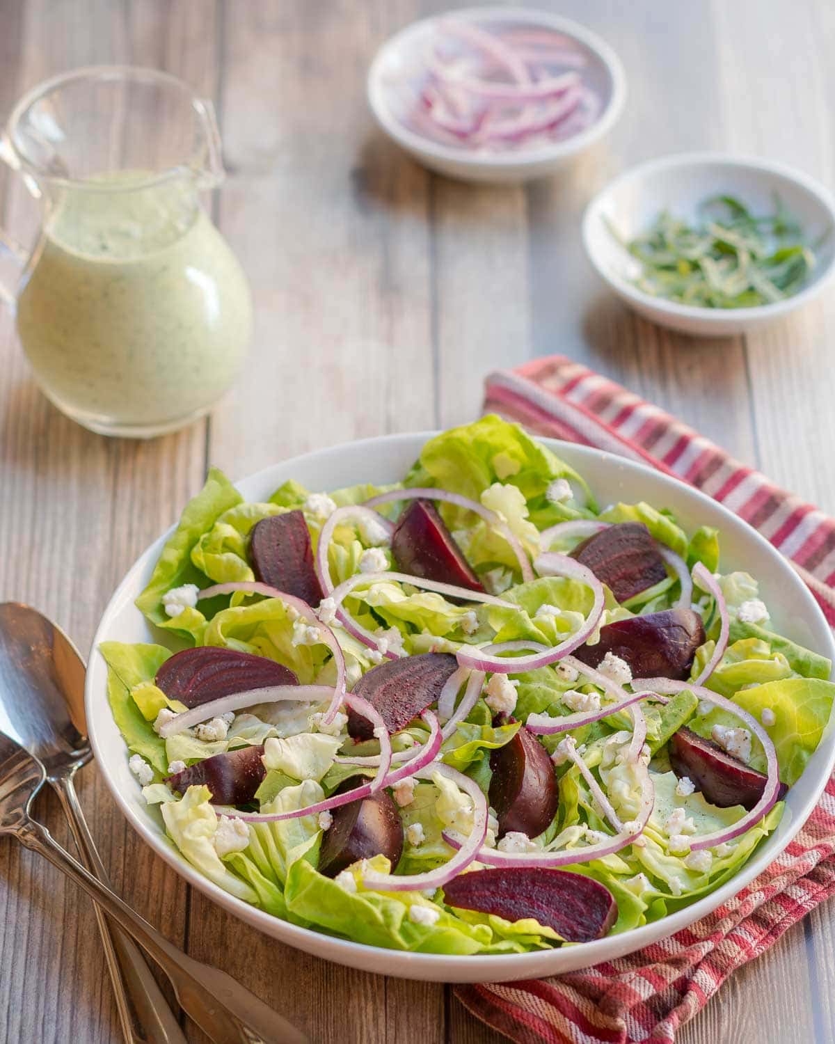 white bowl holding a portion of Roasted Beet Salad with Goat Cheese with Creamy Arugula Dressing on the side