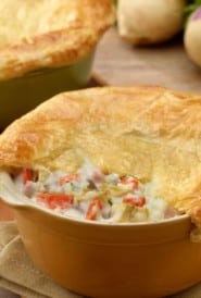 roasted root vegetable pot pie in a tan baking dish, with a corner of the top removed to show the filling