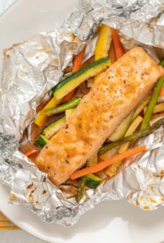 overhead view of salmon and vegetables baked in foil, with foil cut open to show inside