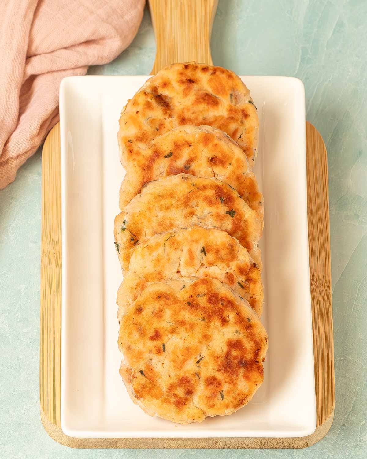 Rectangular platter holding several overlapping salmon patties in one row