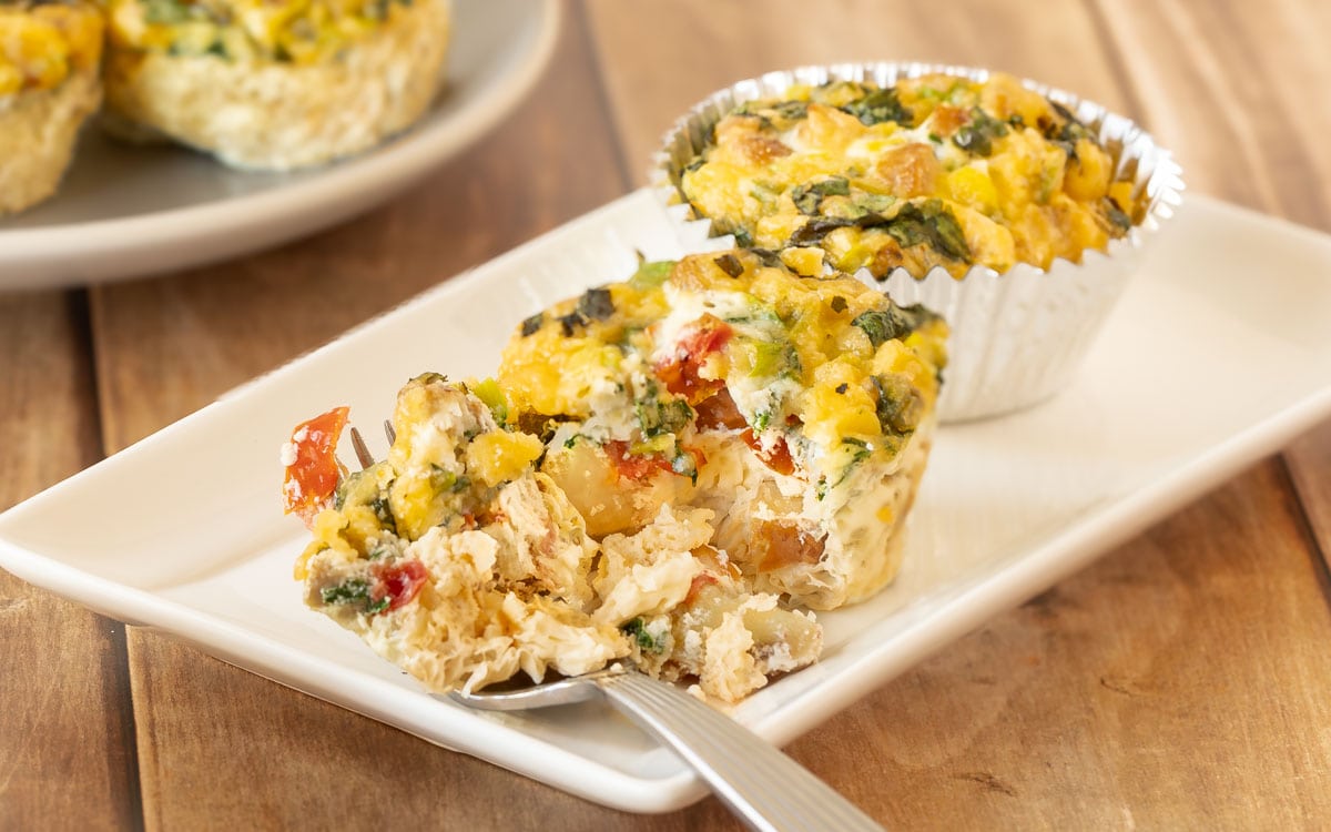 One cut open Sausage, Egg and Cheese Muffin sitting next to another muffin