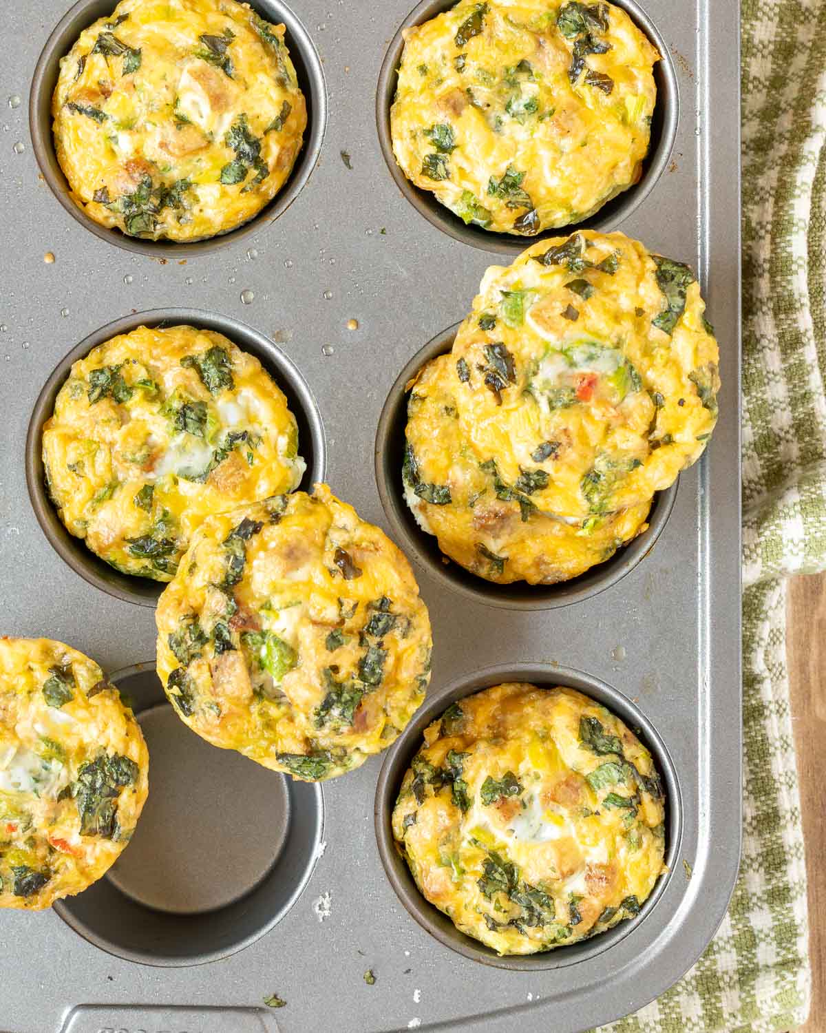Overhead view of Sausage, Egg and Cheese Muffins in muffin pan, with 3 muffins sitting on top