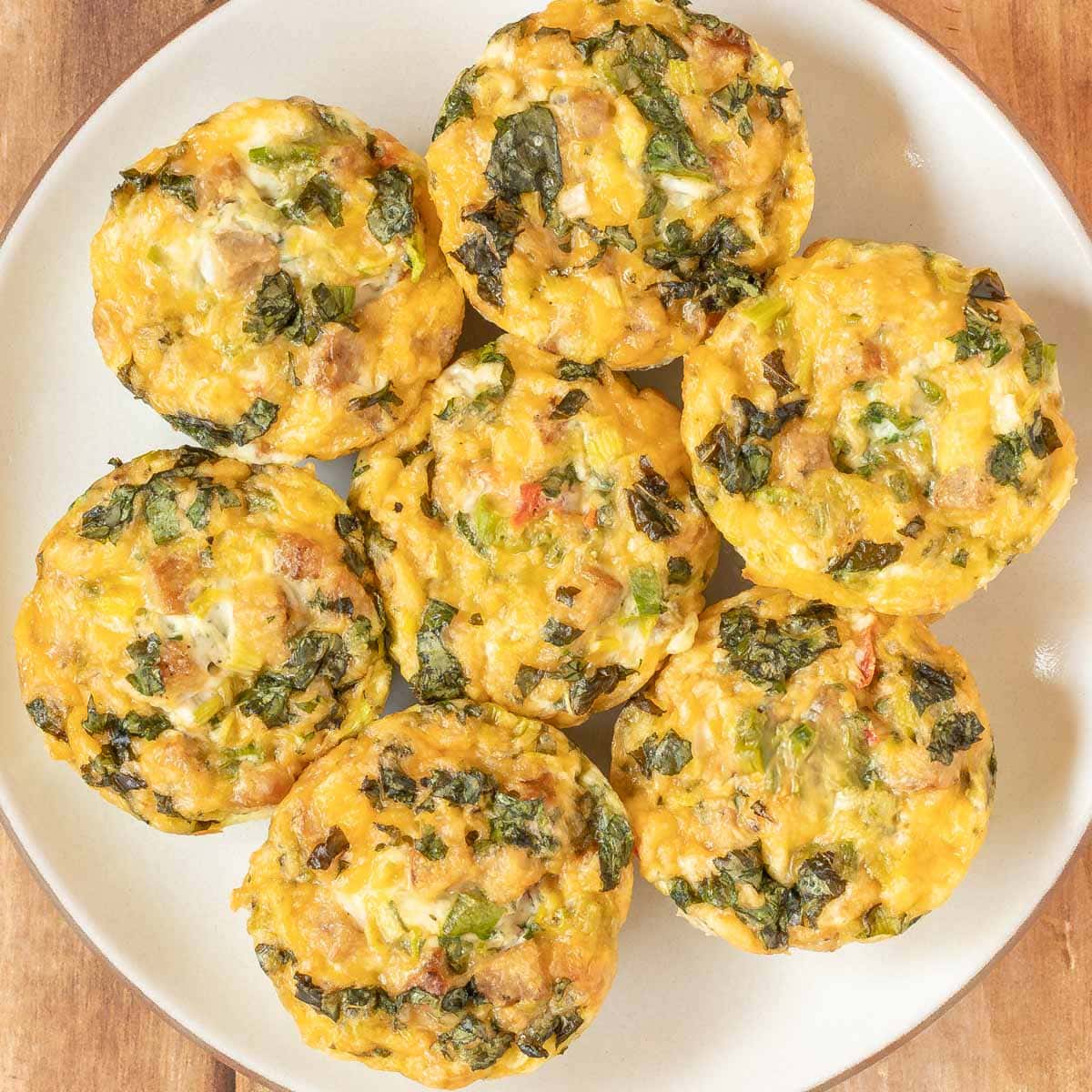 Overhead of seven Sausage, Egg and Cheese Muffins on a white plate