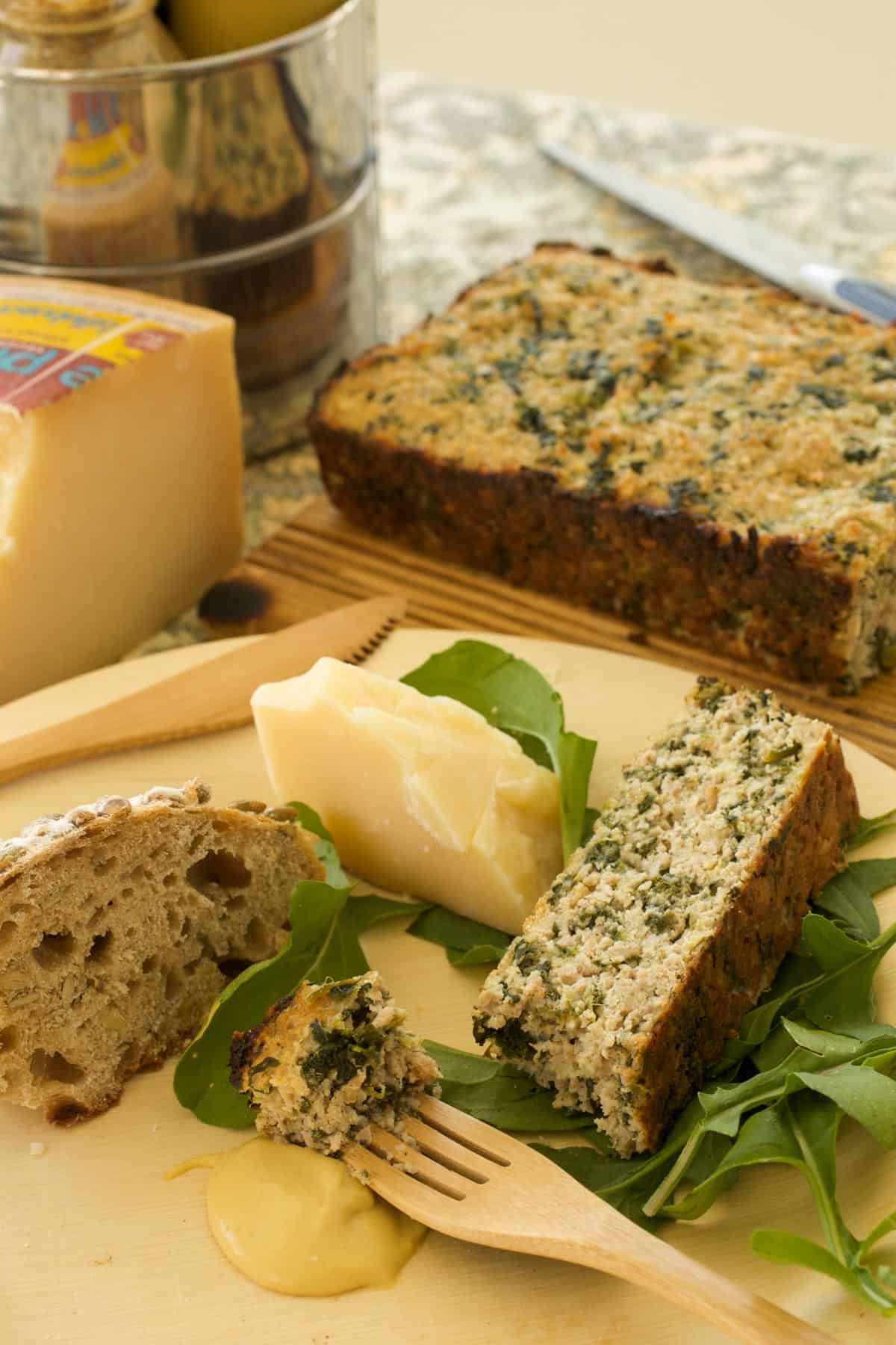 Wooden plate with sliced Sausage and Spinach Torte, alongside a wedge of cheese