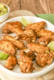 round white platter filled with spicy chicken wings; guacamole in a bowl on the side