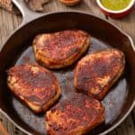 cast iron skillet with Spicy Pork Chops with Chimichurri Sauce on the side