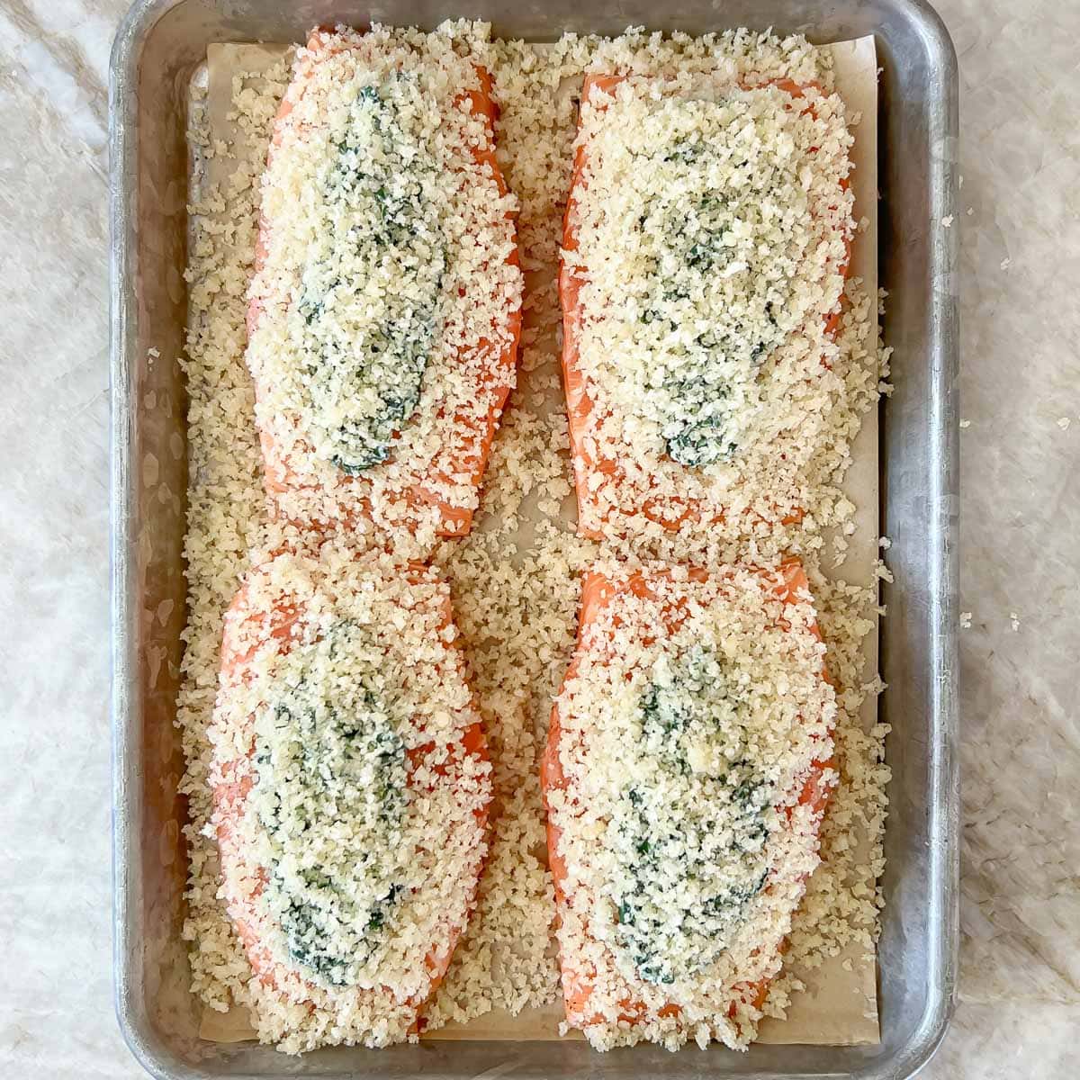 Process shot of stuffed and topped salmon fillets ready for baking