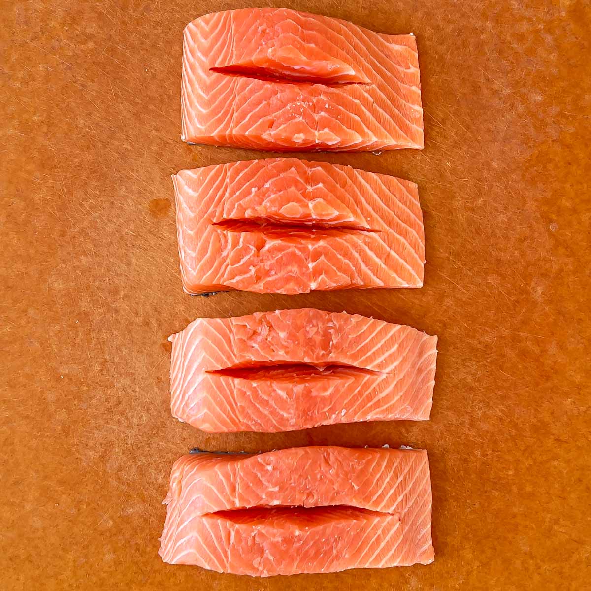 Process shot showing uncooked salmon with slits for stuffing
