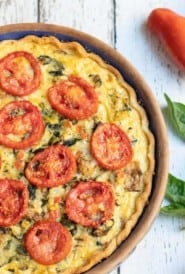 Overhead shot of mushroom, spinach, zucchini pie with sliced tomatoes on top
