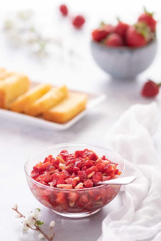 Clear bowl showing Strawberry Topping with slices of lemon bread in the background