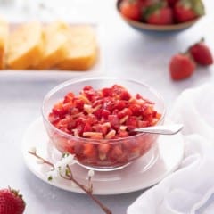 Close up of glass bowl showing Strawberry Topping, with sliced cake in the background