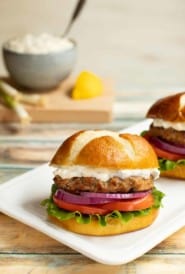 White platter with two Sundried Tomato Turkey Burgers and Lemon-Green Onion Sauce