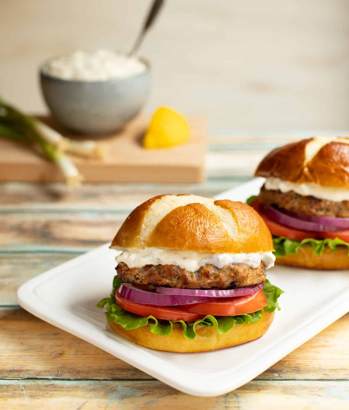 White platter with two Sundried Tomato Turkey Burgers and Lemon-Green Onion Sauce