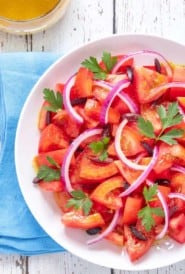 Close up of tomato salad garnished with red onion and parsley