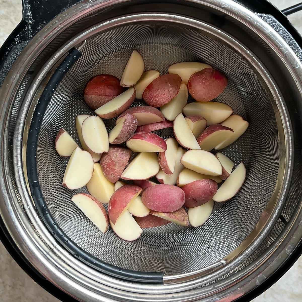 Inside of an Instant Pot holding steamed quartered red-skinned baby potatoes