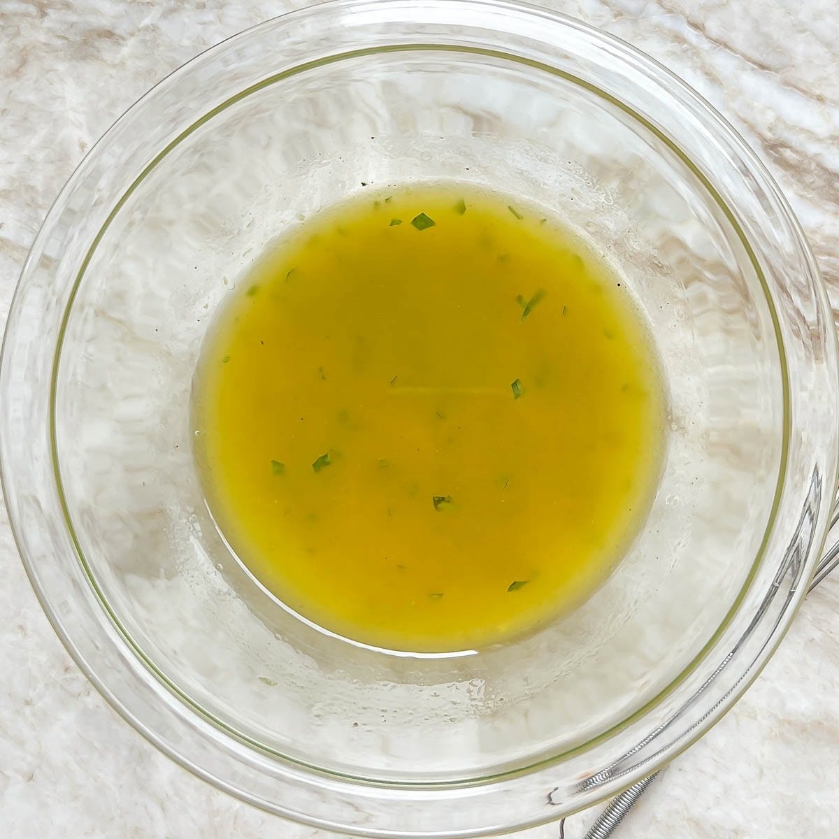 Small glass bowl showing whisked lemon-tarragon vinaigrette dressing