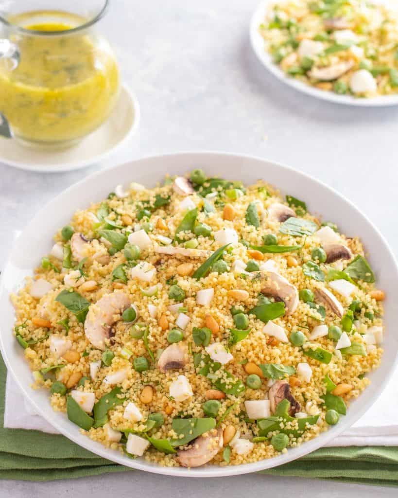 White bowl holding Vegetable Couscous: carafe of Dill Vinaigrette alongside